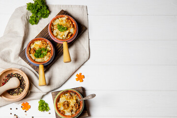  Three servings of hot homemade julienne on a white wooden background, top view, copyspace