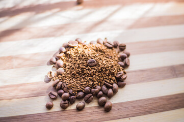 Roasted coffee beans are scattered on a wooden board and instant coffee is scattered inside.