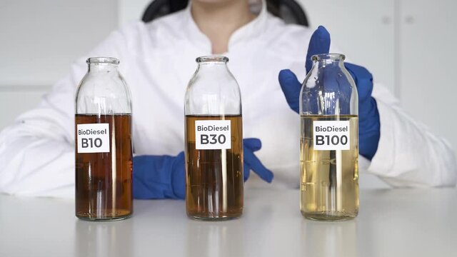 Scientist girl chooses a glass flask with B100 biodiesel