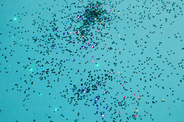 Multicolored glitter on blue background. Blurred christmas abstract background. Copy space.