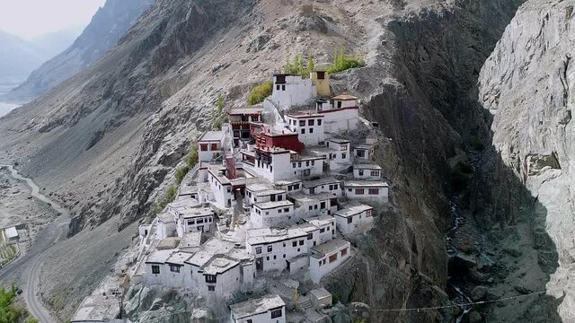 ancient buddhist monastery on a beautiful and remote, rocky mountain landscape. tilt angled top aerial view during daylight.