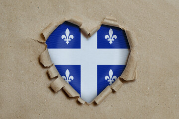 Heart shaped hole torn through paper, showing Quebec flag