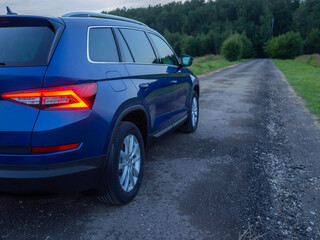 Fototapeta na wymiar Close up rear-side view of blue car in summer evening, nature background