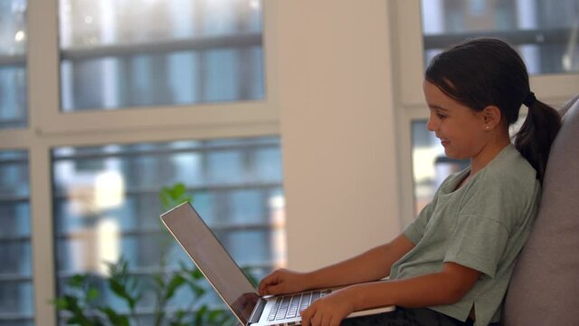 Cute child use laptop for education, online study. Girl has homework at home schooling.