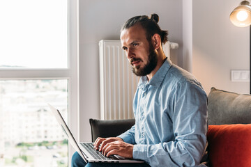 Young man is working on his laptop. Casual businessman in home office working at his laptop.