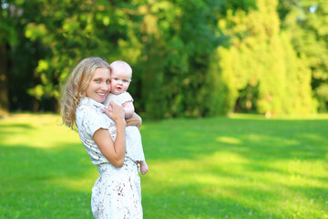 Fototapeta premium Young family with a child in the park. Portrait of mom and daughter outdoors