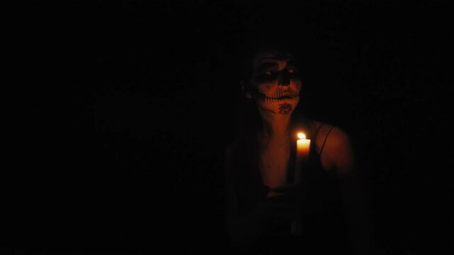 Girls with Katrina Calavera's makeup. A girl in the dim light of a candle is looking for something in the dark. 