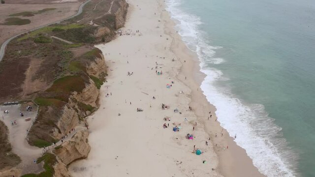 AERIAL: drone, half moon bay beach cliffs and people enjoying the beach, flying forward view