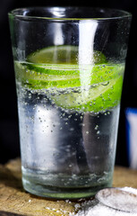 a glass of soda and lime slices in it on a dark background