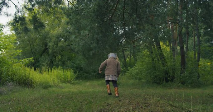 Dziewczynka idzie po polance, myśli i zastanawia się wśr&oacute;d drzew.