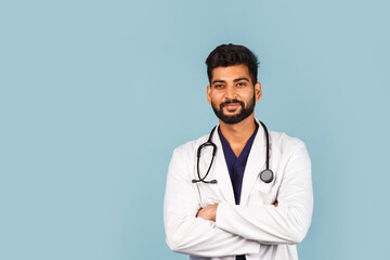 Handsome modern Indian / Asian doctor with stethoscope, in uniform on blue background