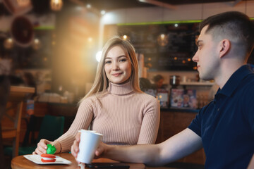 Romantic young couple drinking coffee with the young man eating a biscuit and driking cappuccino