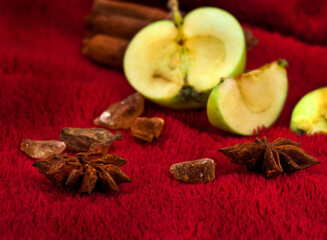 Star anise, brown sugar and apples on a red textile background. Autumn and winter holidays concept. 