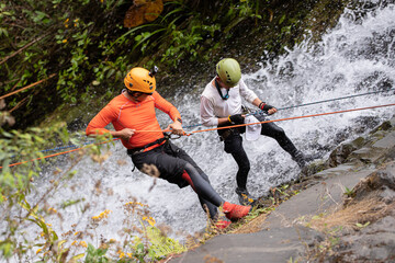 Two Amateur Man rappelling down a waterfall