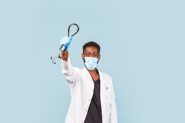 happy African American male doctor with stethoscope wearing mask and gloves on blue background. winner