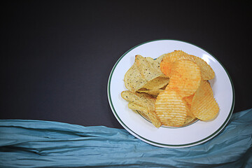 Potato chips in black background white plate