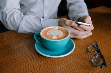 Shot of business staff and blue cup of coffee with picture on a foam, blue glass and mobile phone