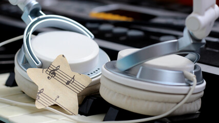 A star of paper music notes and white headphones on the piano.