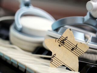 A star of paper music notes and white headphones on the piano.