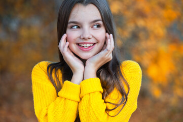 Beautiful girl walking outdoors in autumn. Smiling girl collects yellow leaves in autumn.