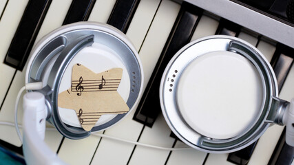 A star of paper music notes and white headphones on the piano.