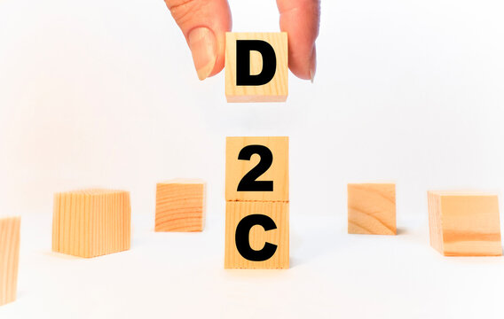 The hand puts the cube block with the inscription D2C. Business to business concept background.