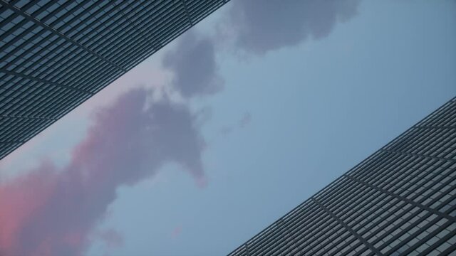 Low angle rotating camera with a airplane flying over the top big city skyscraper office buildings