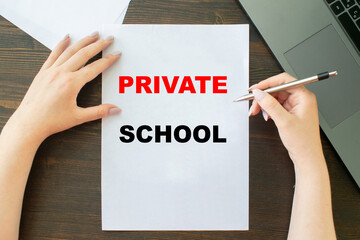 PRIVATE SCHOOL inscription on sheet a4, the girl writes next to the laptop
