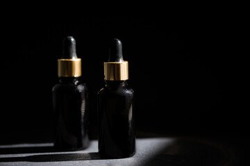 Obraz na płótnie Canvas Pipette black glass dropper bottle with golden elements on the dark background