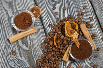 Coffee beans. Ground coffee in containers and spices. On a surface of brushed pine boards painted black and white.