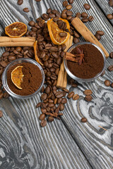 Coffee beans. Ground coffee in containers and spices. On a surface of brushed pine boards painted black and white.