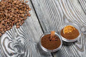 Coffee beans. Ground coffee in containers and spices. On a surface of brushed pine boards painted black and white.