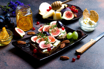 Fototapeta na wymiar Fig sandwiches with mascarpone and honey, with grape, pecan nuts, red currant, chees and pears, closeup