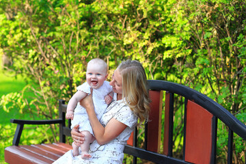 Fototapeta premium Young family with a child in the park. Portrait of mom and daughter outdoors