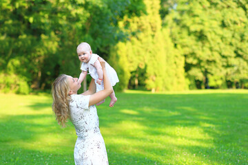 Young family with a child in the park. Portrait of mom and daughter outdoors