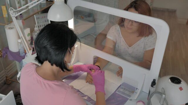 Tratamiento de manicura a ni&ntilde;a con protecci&oacute;n de mascarilla y mampara en cl&iacute;nica de belleza