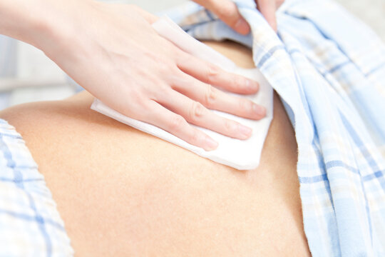 患者の体を拭く看護師