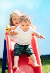 Fototapeta na wymiar Girl pushing her little brother off the water slide