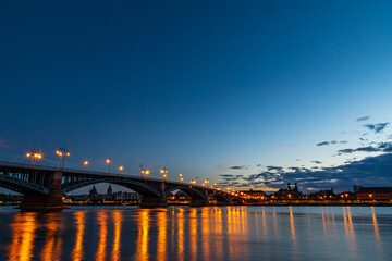 Obraz premium The illuminated Theodor Heuss Bridge that crosses the Rhine between Mainz and Wiesbaden at night. In the background the silhouette of Mainz
