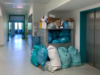 in a corner of a hospital corridor different garbage bags are piled up