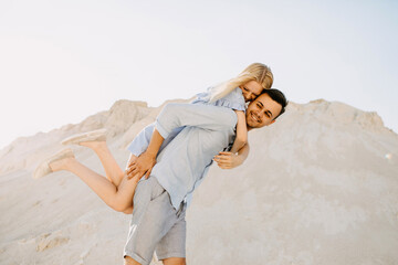 Young romantic couple outdoors. Man giving a piggyback riding, both laughing.