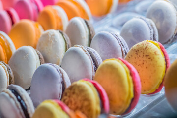 Rows of bright colorful macarons cakes for sale on counter of candy shop, market, cafe or bakery. Dessert, biscuit, sweet food and traditional french cuisine concept