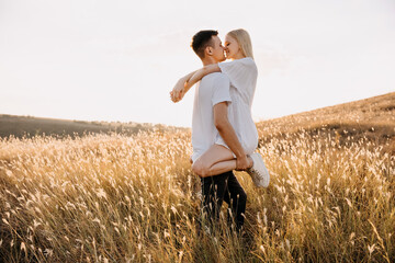 Young romantic couple in a field having fun, hugging and kissing.