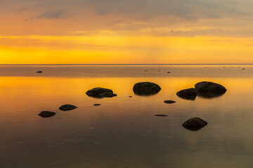 Fototapeta na wymiar Orange sunset rocky shore of Baltic sea.
