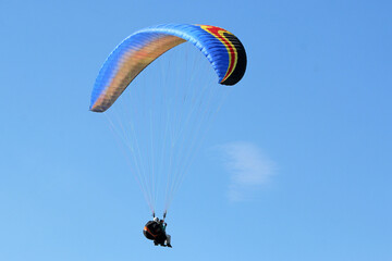 Tandem Paraglider flying wing in a blue sky	