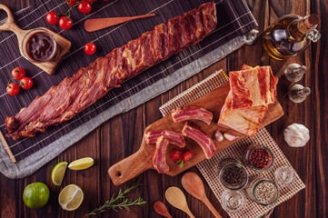 Smoked pork ribs with bacon , bbq sauce and ingredients on a wood background - Top view