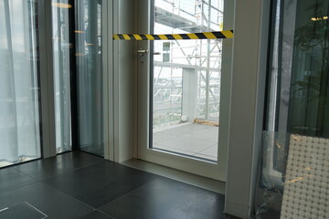 Closed door and blocked with barrier tape to the terrace that is being reconstructed and covered with scaffolding and construction material.