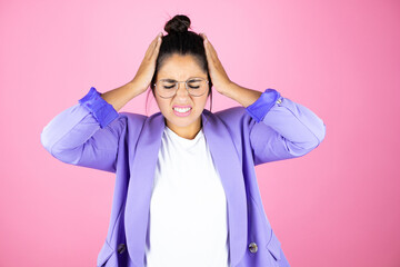 Young beautiful business woman over isolated pink background suffering from headache desperate and stressed because pain and migraine with her hands on head