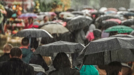 Abstract silhouettes of the people walking on a rain under umbrellas, street scene, back view, blurred background. Concept of seasons, weather, city lifestyle © svetlanais