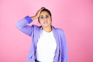 Young beautiful business woman over isolated pink background putting one hand on her head smiling...